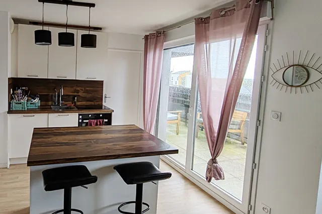 Cuisine ouverte avec îlot, donnant sur un balcon